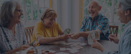 older people playing cards around a table